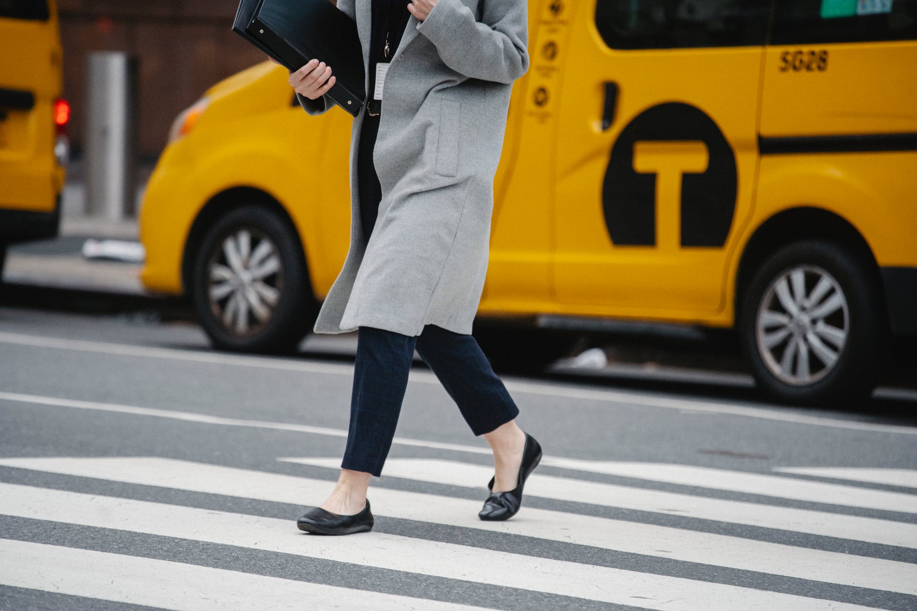 crop faceless woman crossing road in downtown