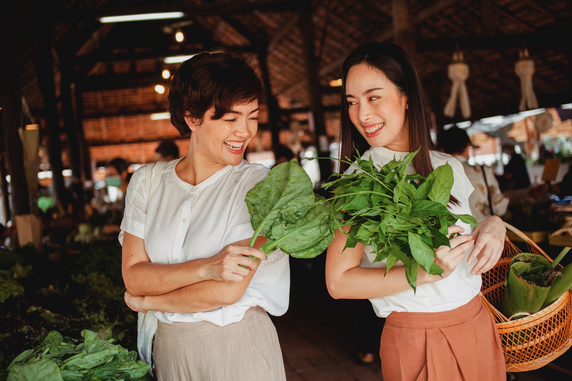 glad asian buyers with fresh green herbs in bazaar