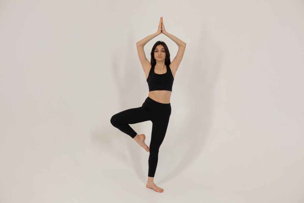 serious woman doing yoga in white studio
