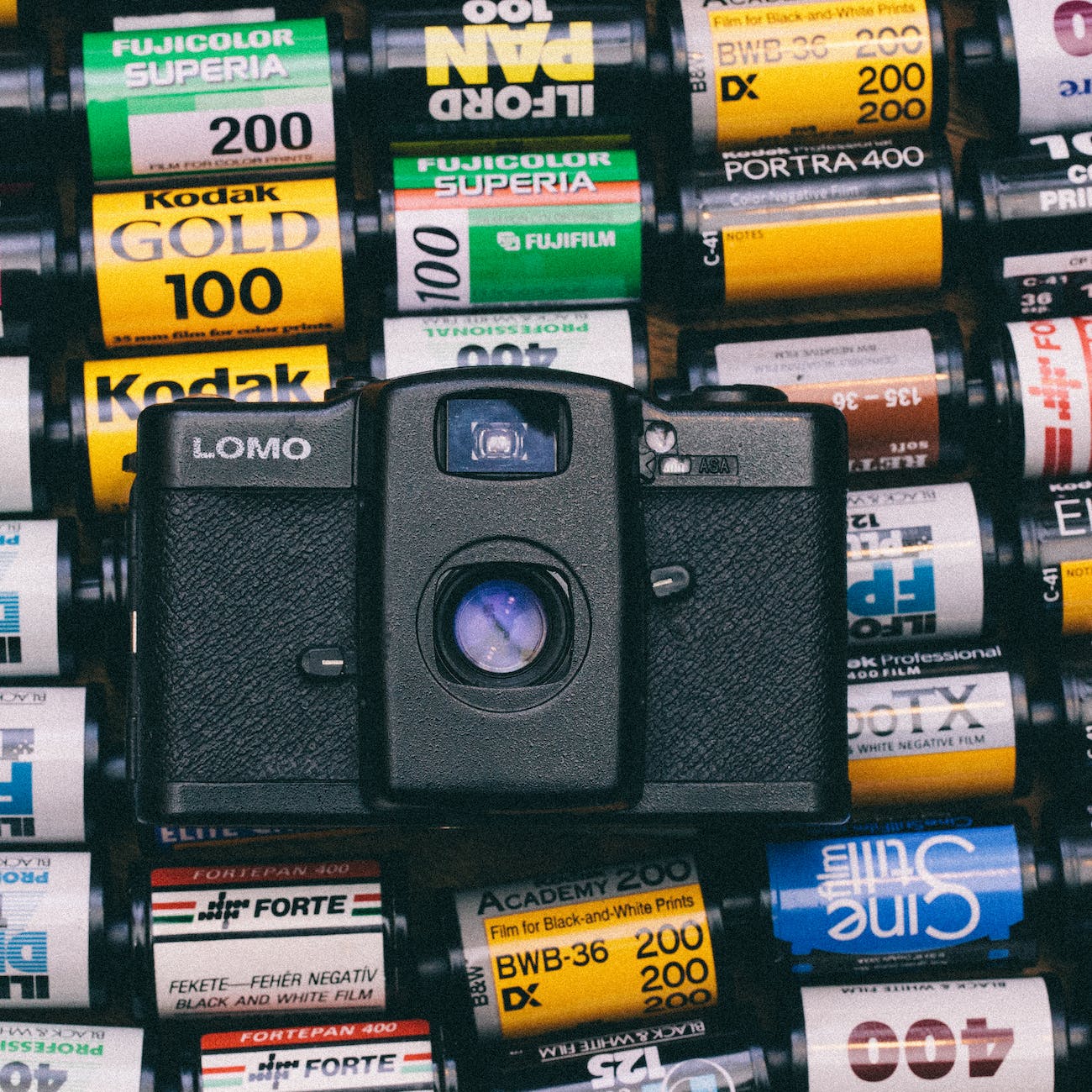 black lomo camera on top of photo films lot