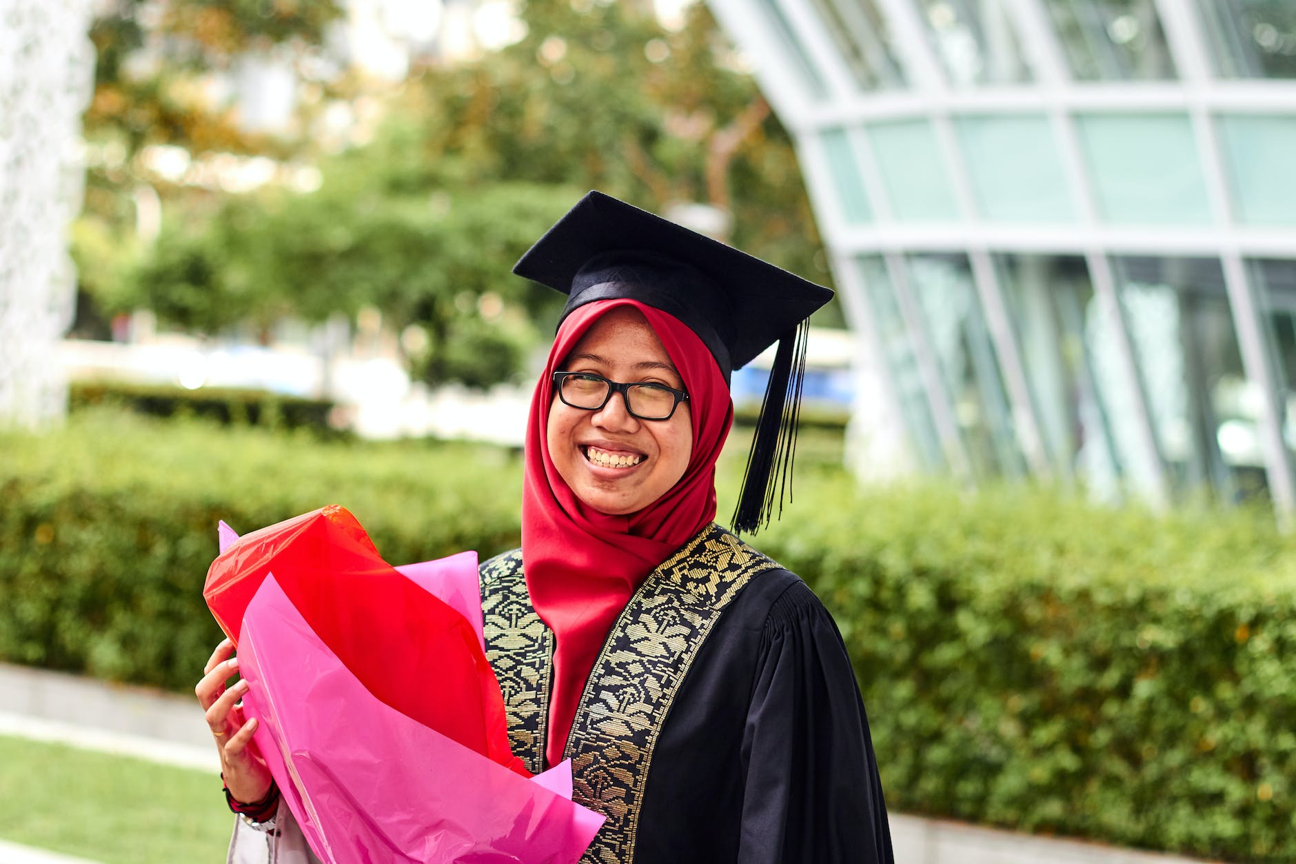 woman wearing academic dress while holding flowers