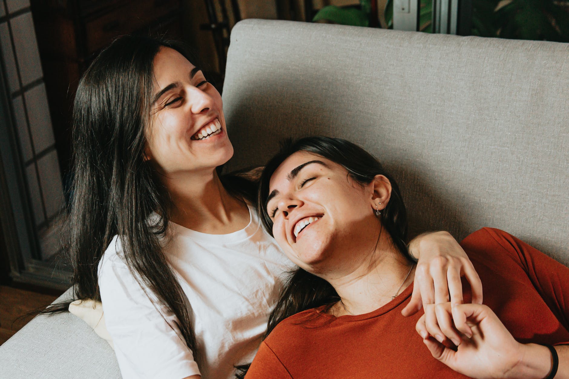 happy women lying on couch holding hands