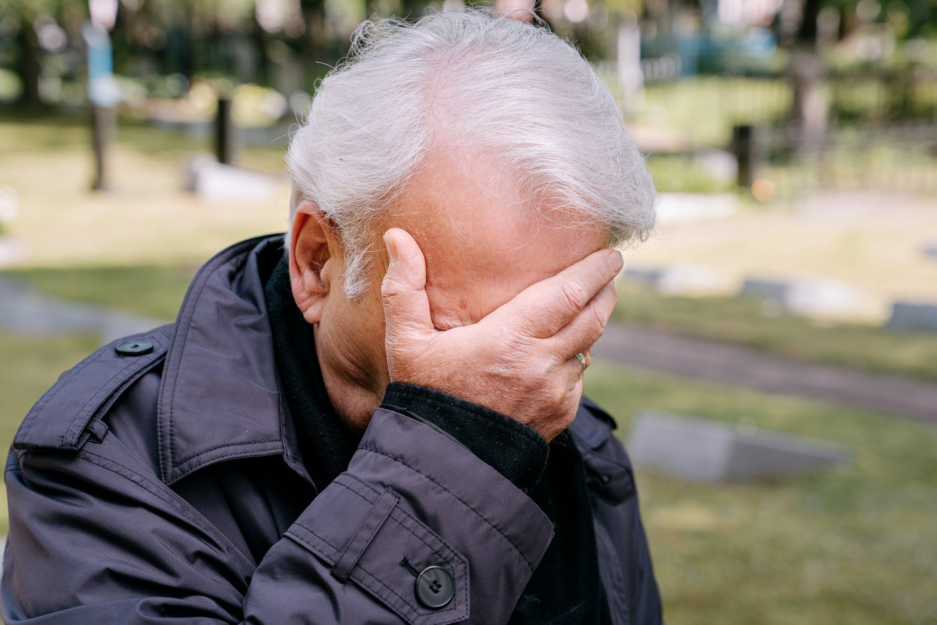 an elderly man covering his face