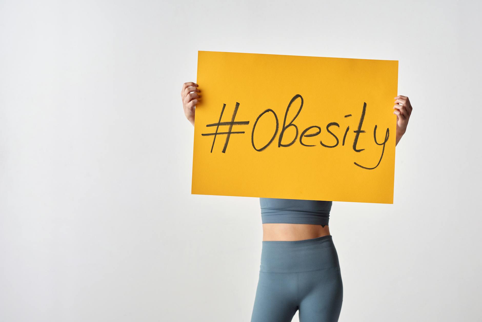 woman holding yellow cardboard with obesity