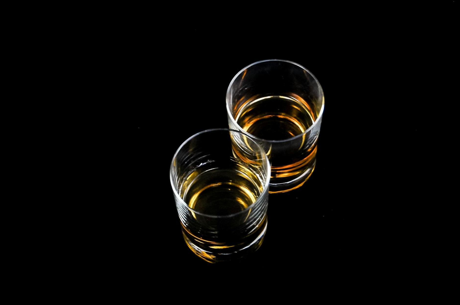 two clear shot glasses filled with liquors