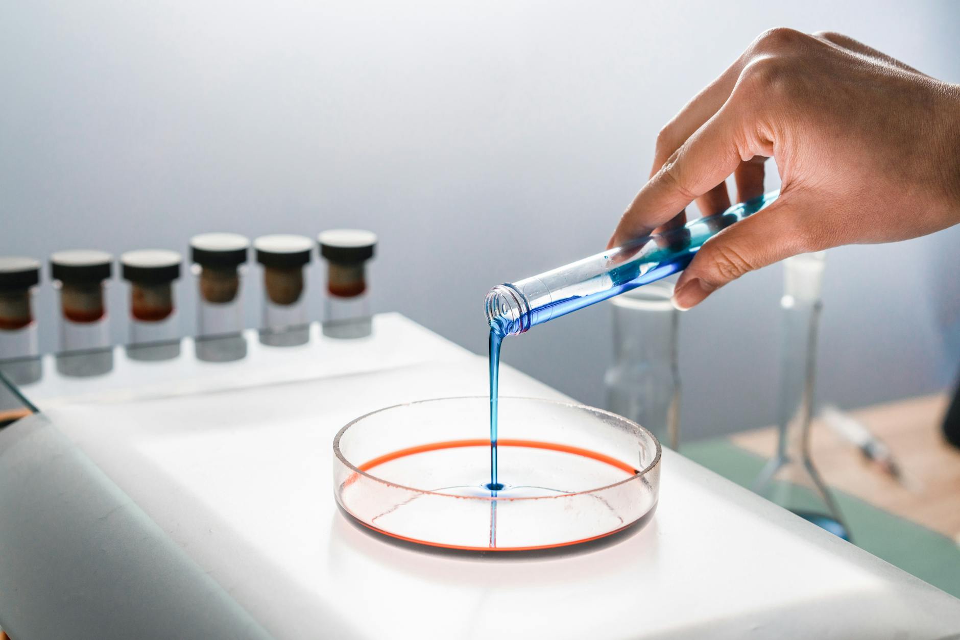 person pouring blue liquid into a glass container