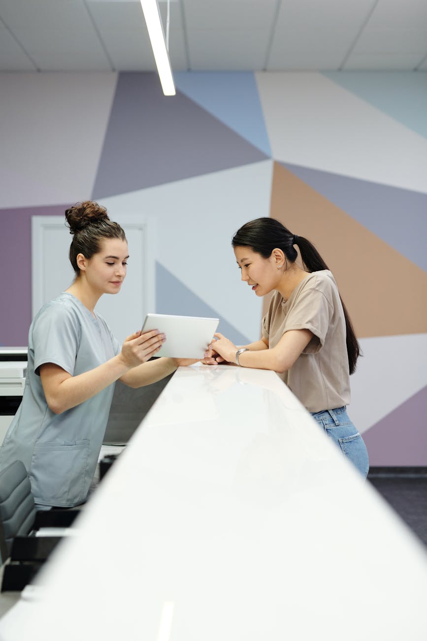 a receptionist showing a woman a tablet