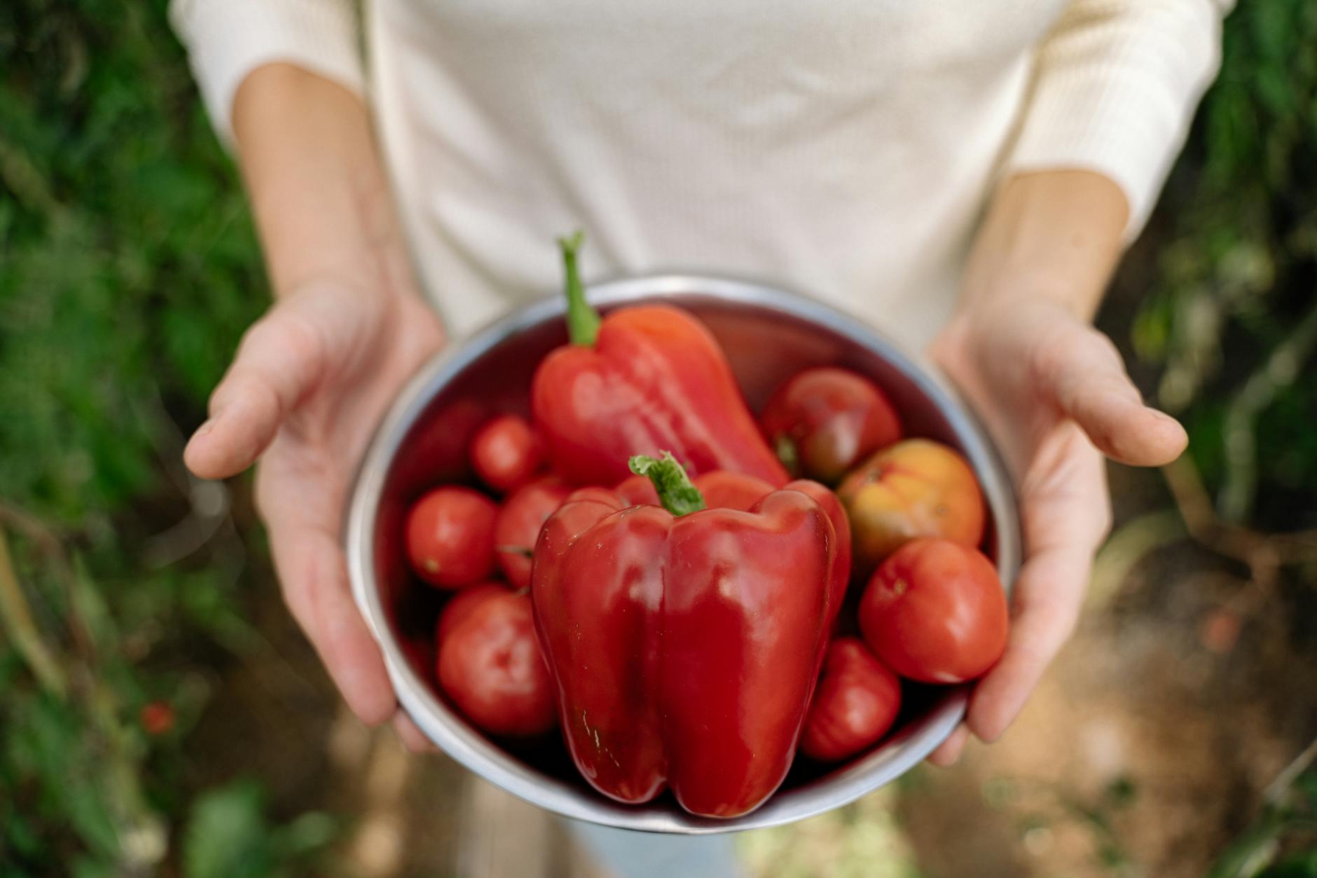 a woman holding a bow of tomatoes and bell peppers