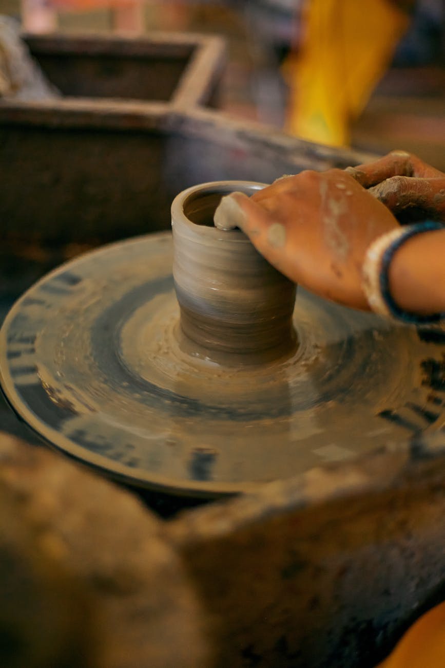 close up of hands crafting pottery on a wheel