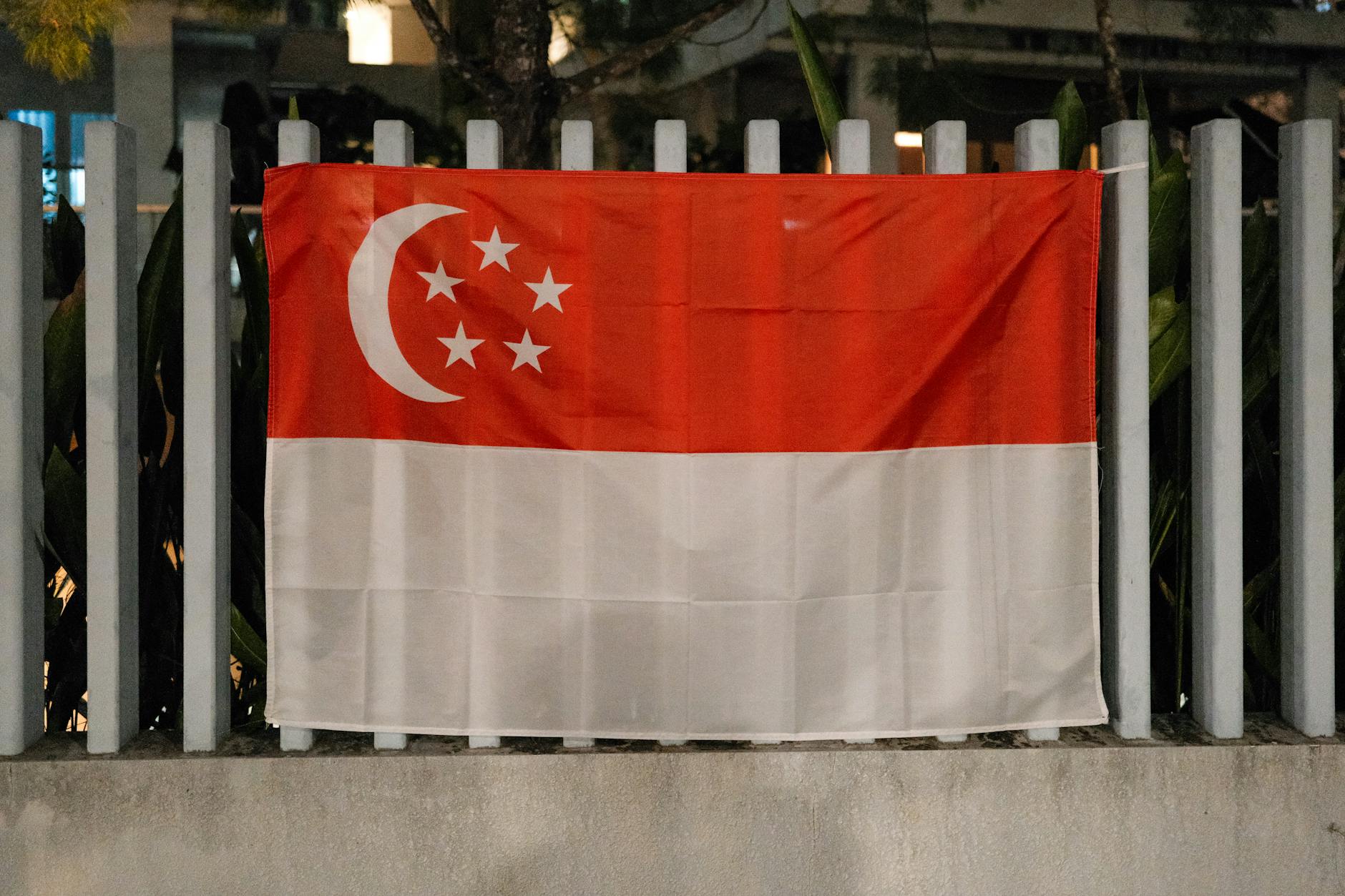 singapore national flag on metal fence at night