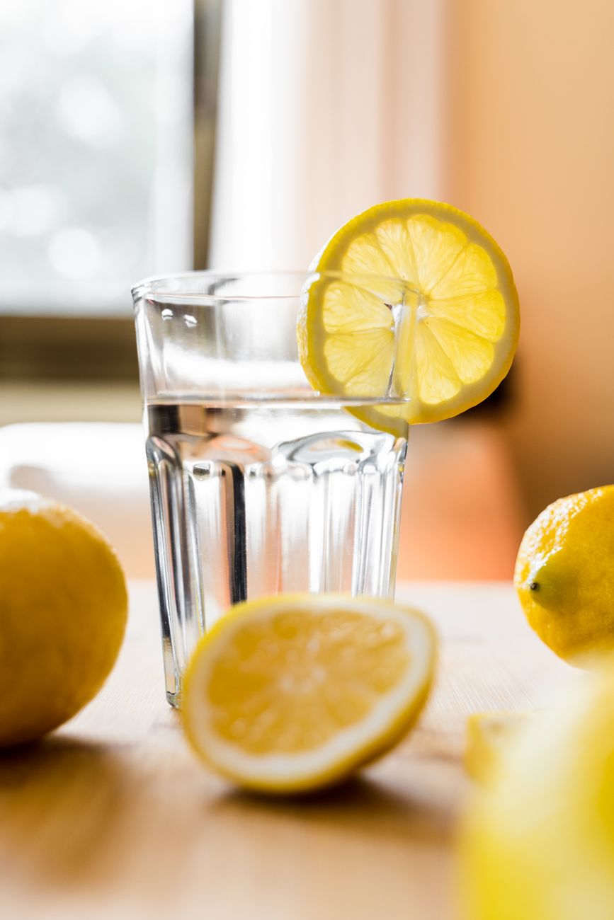 glass of cold water with lemon placed on table