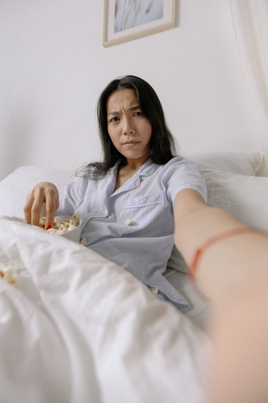 a woman in bed with a bowl of popcorn